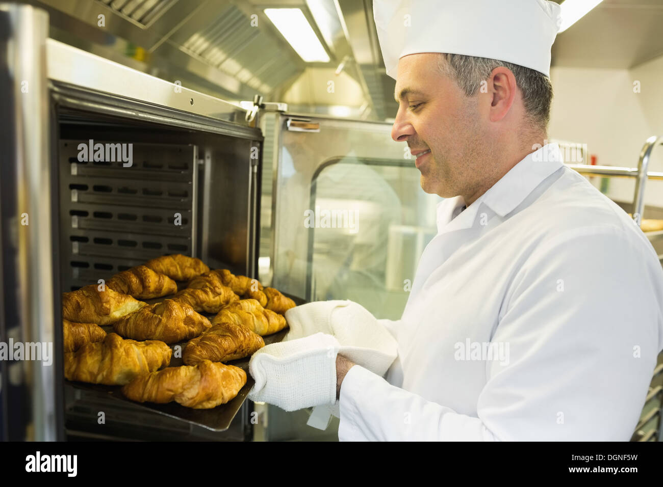 Coppia baker mettendo qualche croissant in un forno Foto Stock