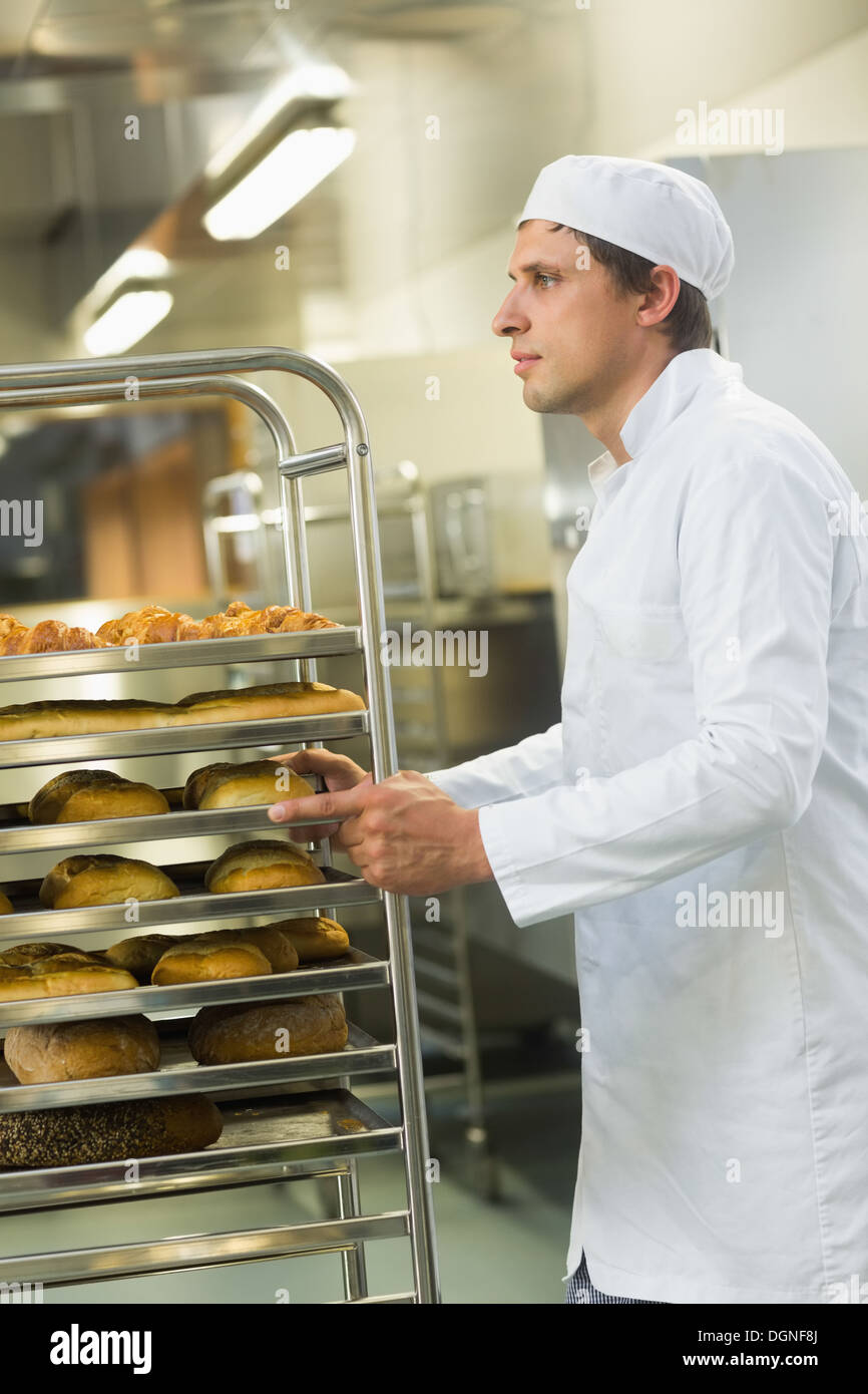 Bel giovane baker spingendo un carrello Foto Stock