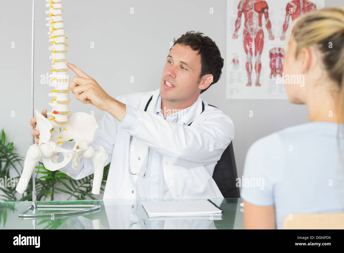 Bello medico che mostra un paziente qualcosa sul modello dello scheletro Foto Stock