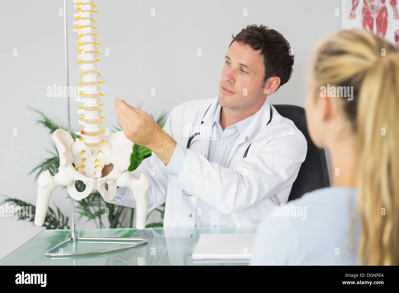 Medico di contenuto che mostra un paziente qualcosa sul modello dello scheletro Foto Stock