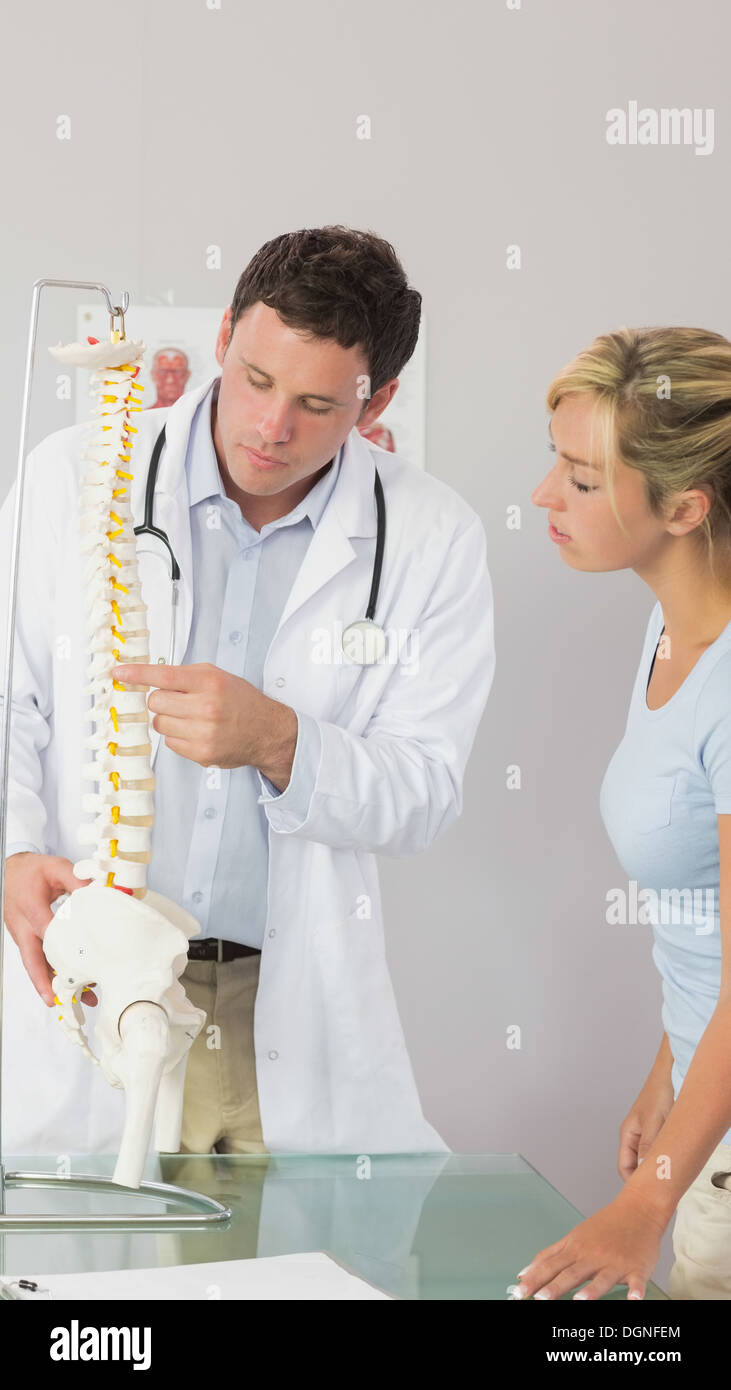 Medico grave mostra un paziente qualcosa sul modello dello scheletro Foto Stock