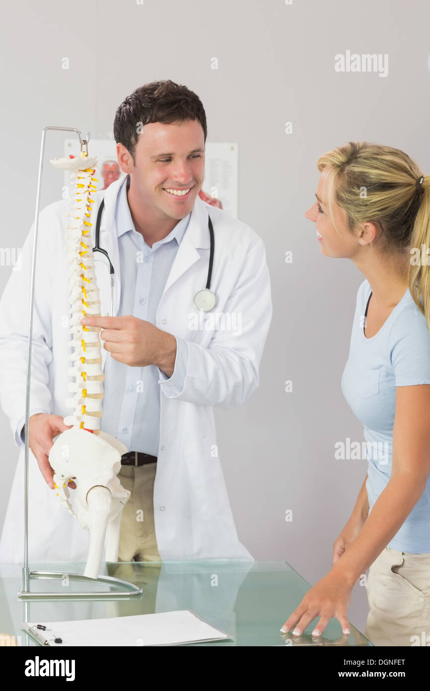 Allegro medico che mostra un paziente qualcosa sul modello dello scheletro Foto Stock