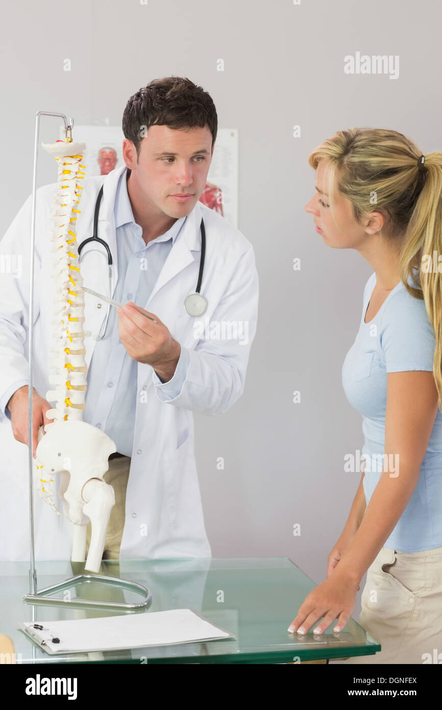 Calma medico che mostra un paziente qualcosa sul modello dello scheletro Foto Stock