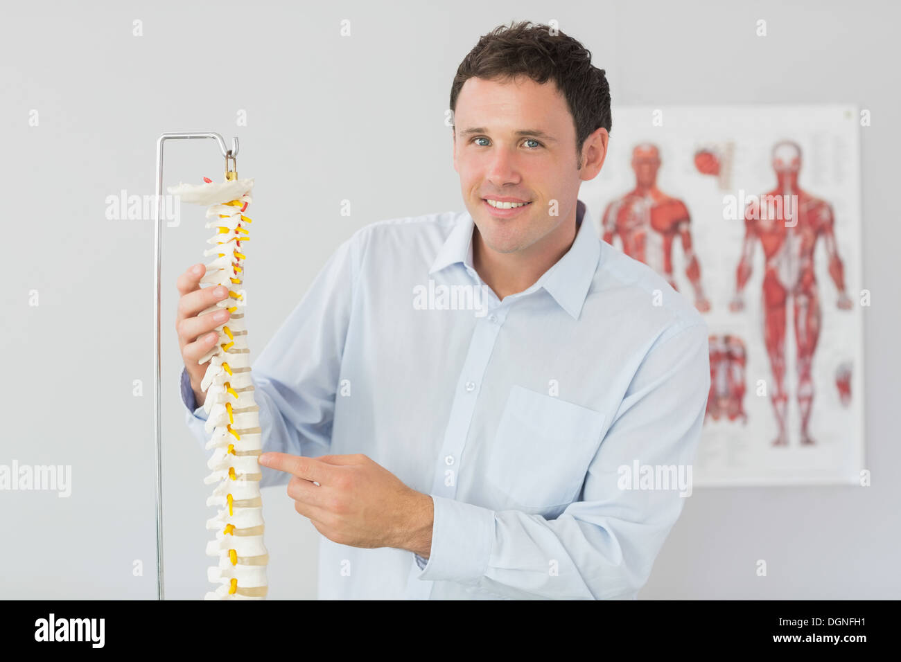 Bello sorridente medico puntando al modello dello scheletro Foto Stock