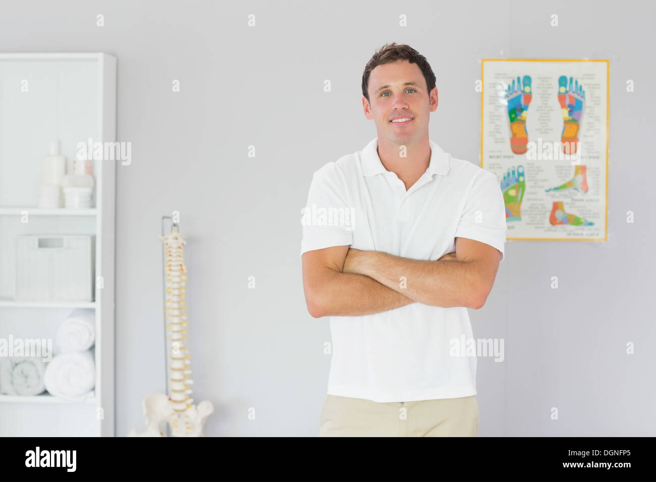 Bello sorridente fisioterapista in piedi con le braccia incrociate Foto Stock