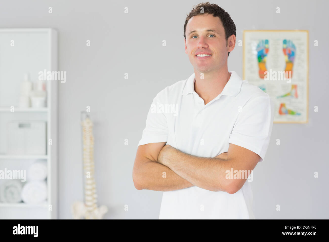 Bello felice fisioterapista in piedi con le braccia incrociate Foto Stock