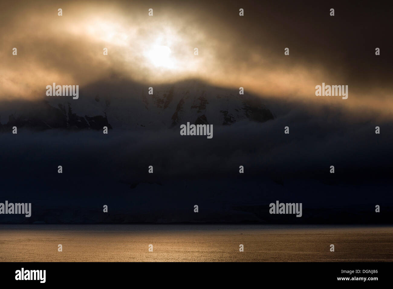 Bassa-standing sole che splende attraverso la copertura nuvolosa denso, Errera Channel, Penisola Arctowski, Penisola Antartica, Antartide Foto Stock