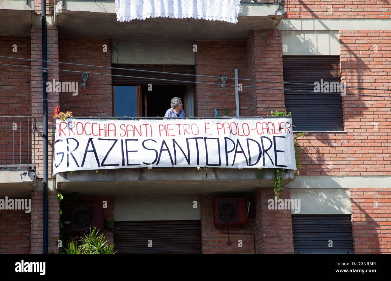 Donna locale con banner sul balcone per Papa Francesco Benvenuti a Cagliari, Sardegna - 22 Settembre 2013 Foto Stock