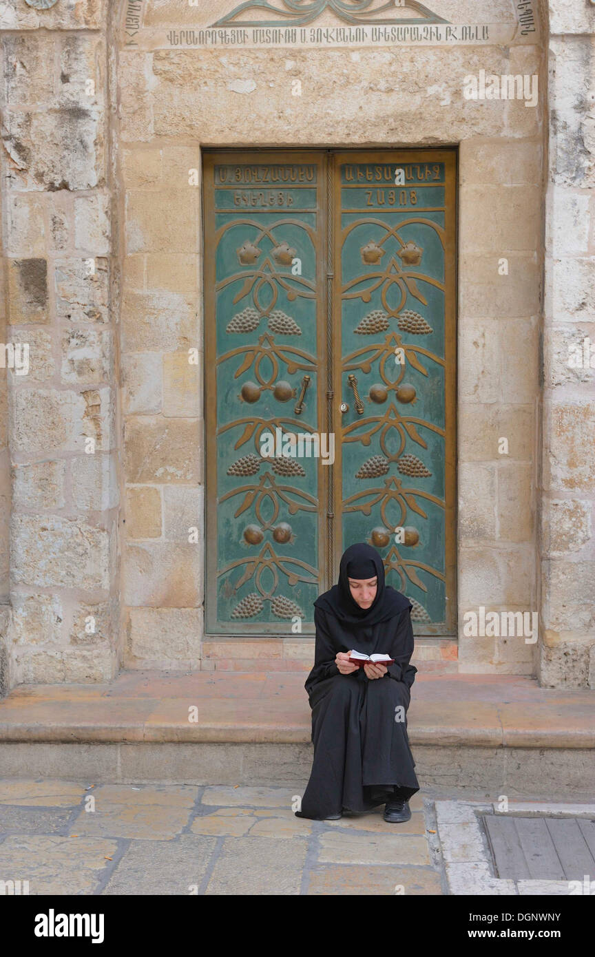 Chiesa russo-ortodossa nun pregando davanti alla porta della chiesa del Santo Sepolcro, Quartiere Cristiano nella vecchia città di Foto Stock