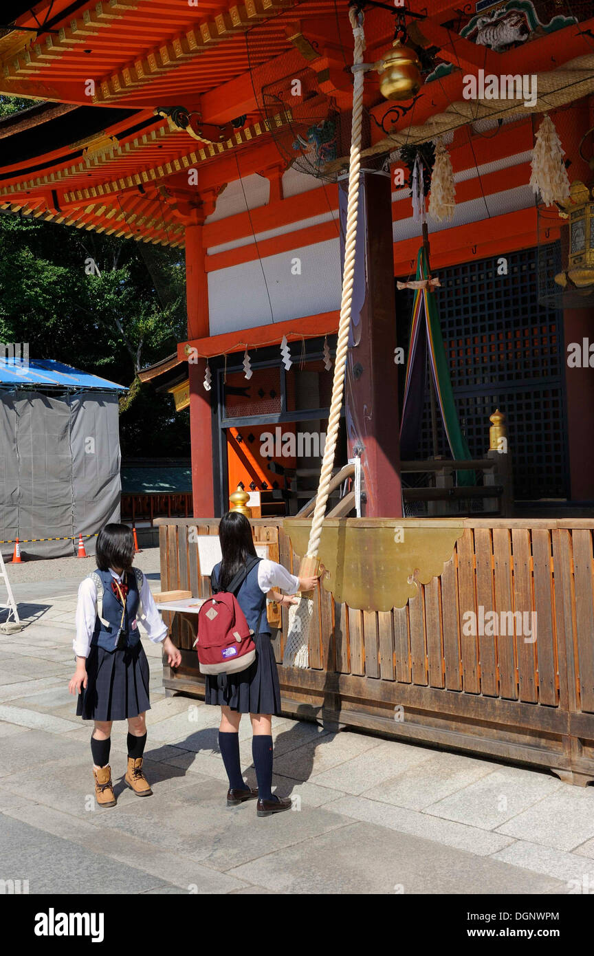 Gli studenti che indossano uniformi di scuola suona su un santuario per attirare gli spiriti' l attenzione su di essi, il santuario Yasaka Foto Stock