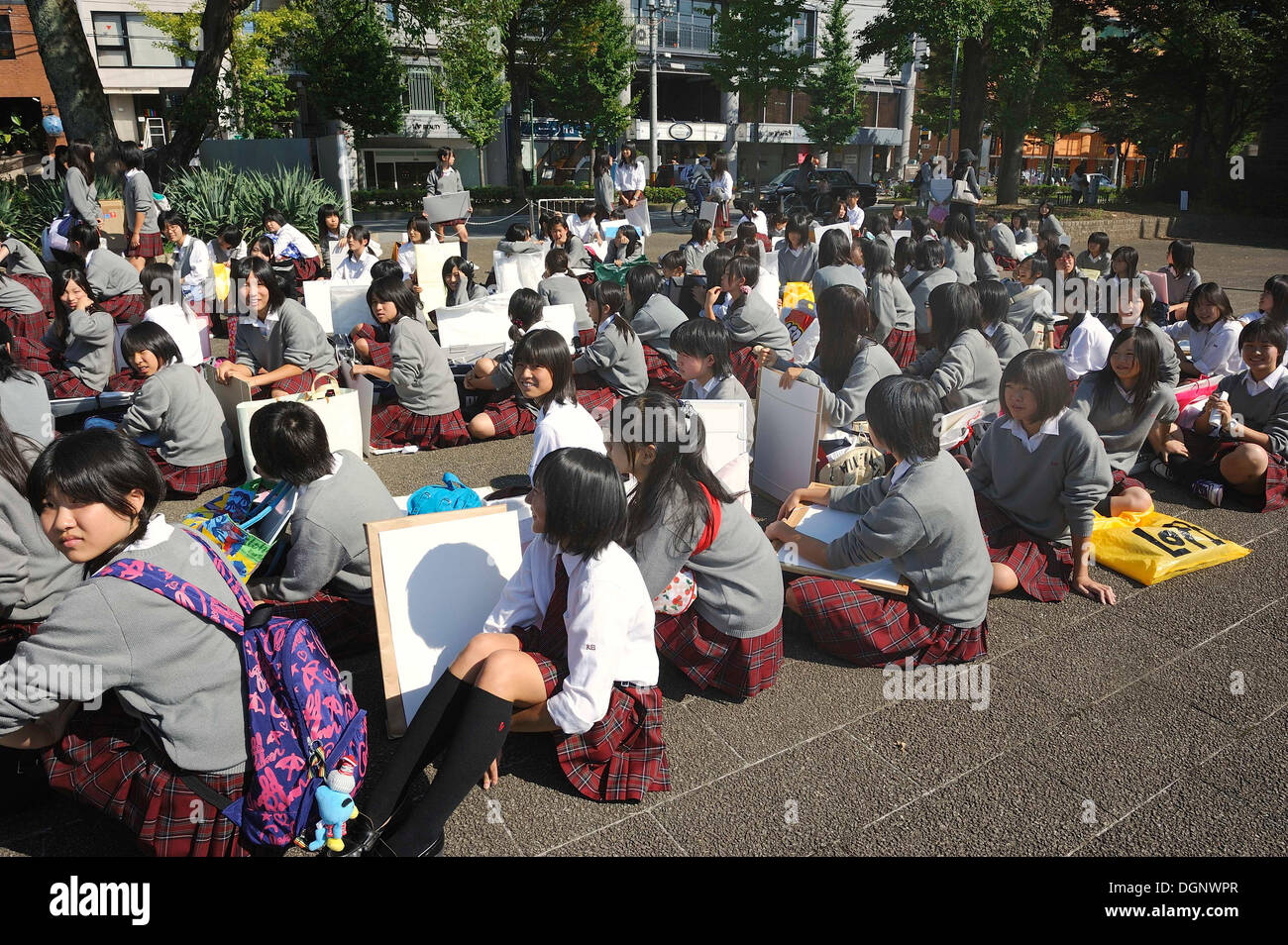 Gli studenti che indossano uniformi scolastiche frequentando lezioni di arte nel Giardino Botanico, in attesa seduto per l'apertura del cancello, Kyoto Foto Stock