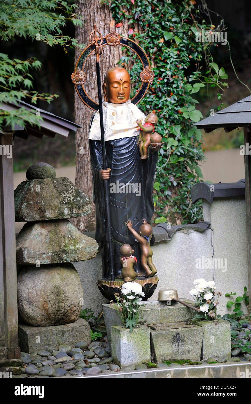 Jizo buddista statua di bib e alo, patrono dio dei figli, con un bambino tra le sue braccia e i bambini ai suoi piedi Foto Stock
