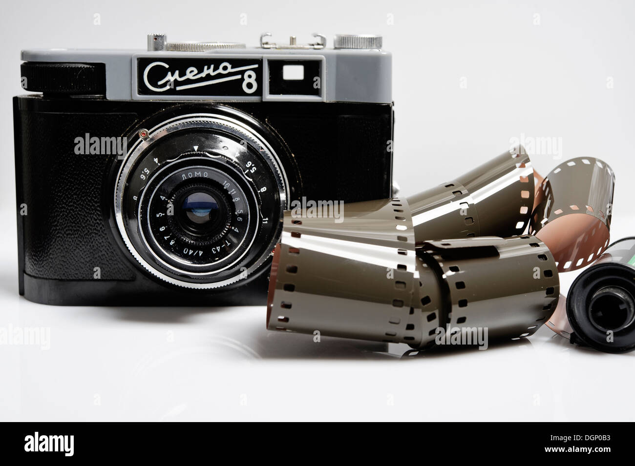 La lente di una fotocamera 35 mm. Apparecchiatura analogica e il negativo della pellicola. Lente sullo sfondo luminoso. Foto Stock