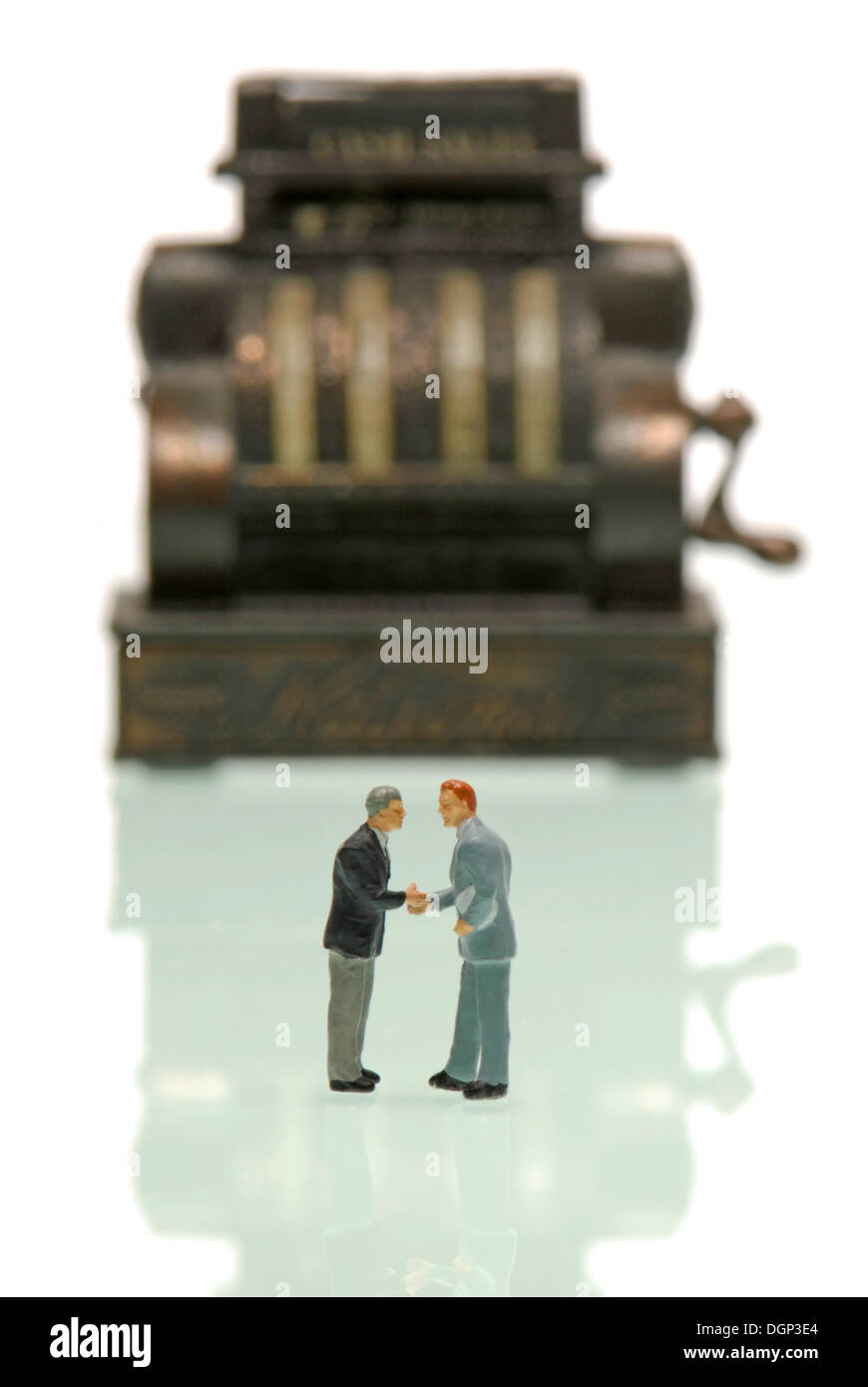 Imprenditori figurine stringono le mani nella parte anteriore del registratore di cassa, immagine simbolica per il business Foto Stock