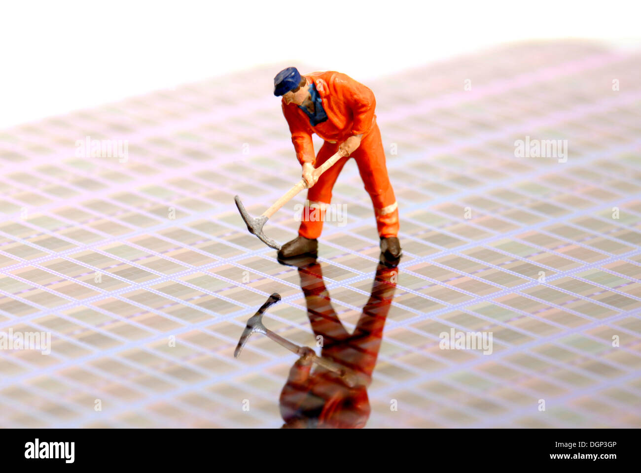 Un lavoratore edile figurina in piedi su una fetta di silicio del componente elettronico, piastra di semiconduttore Foto Stock
