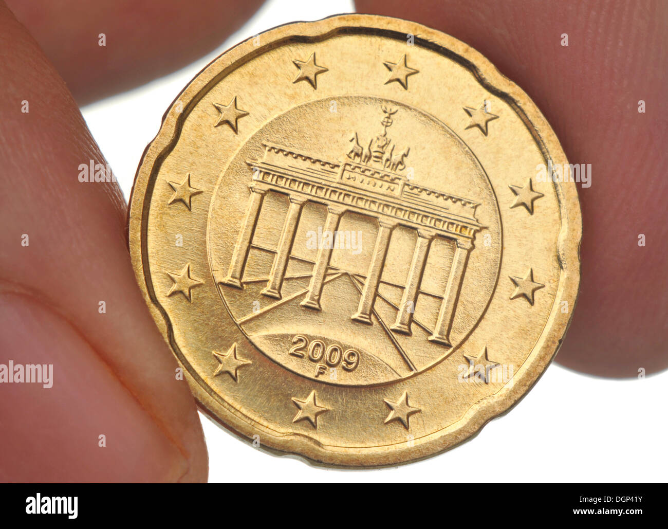 Dita tenendo un venti-cento euro moneta con la Porta di Brandeburgo, macro Foto Stock