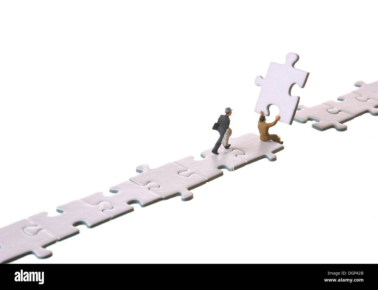 Le figure di uomini di affari di costruire un ponte con i pezzi del puzzle, immagine simbolica per i collegamenti Foto Stock