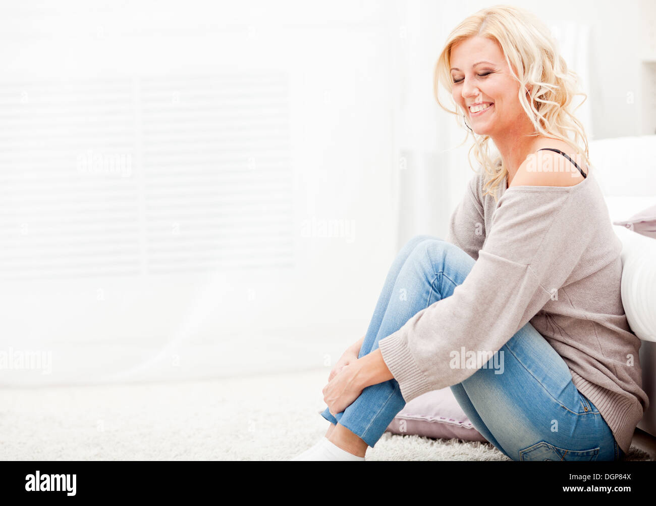 Sorridente ragazza seduta su un tappeto Foto Stock