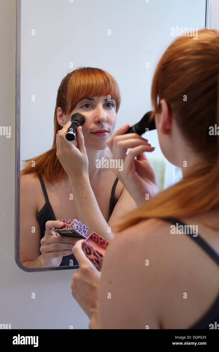Metà donna adulta applicando blusher in specchio Foto Stock