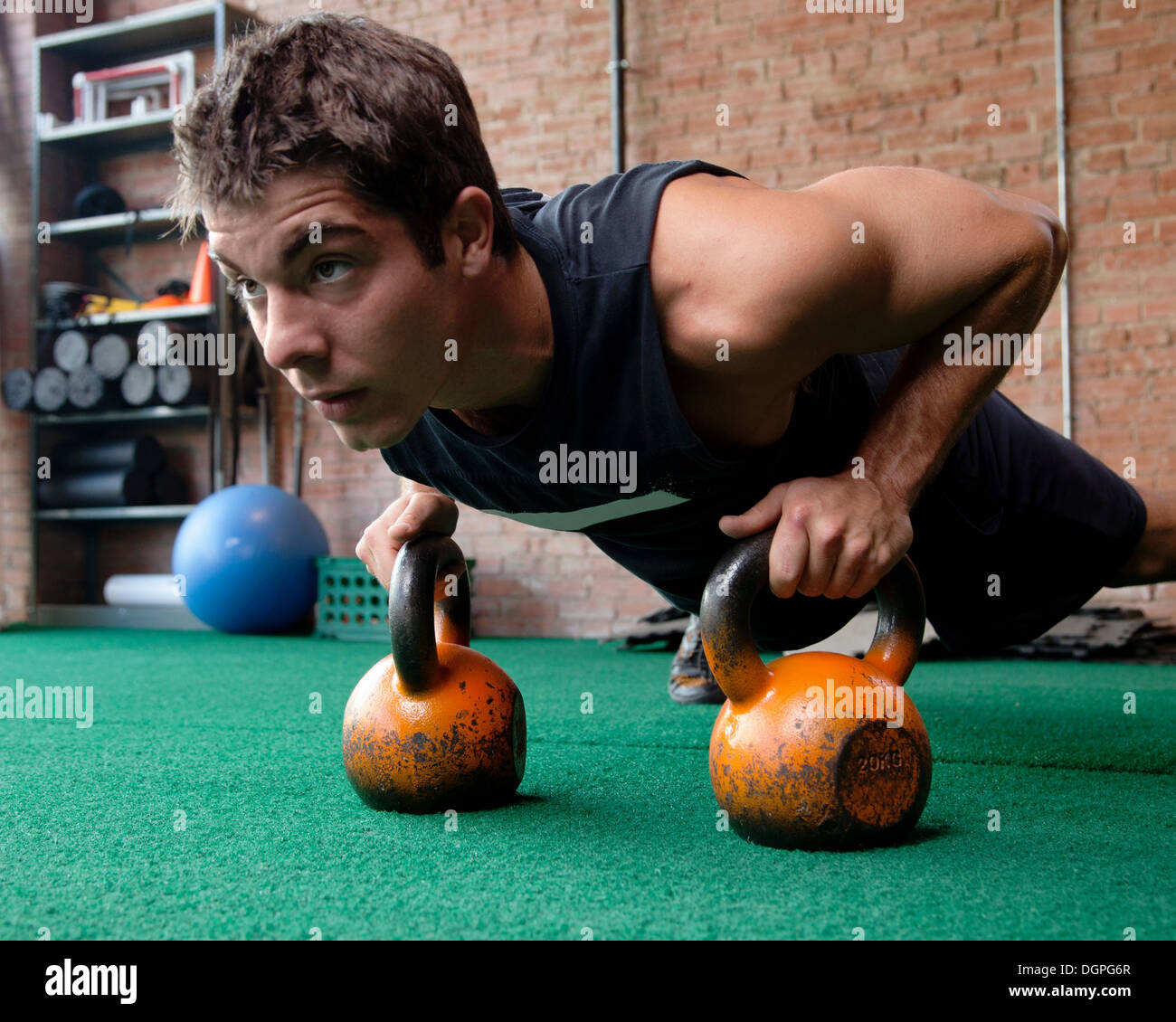 Maschio bodybuilder facendo premere up utilizzando kettlebells Foto Stock