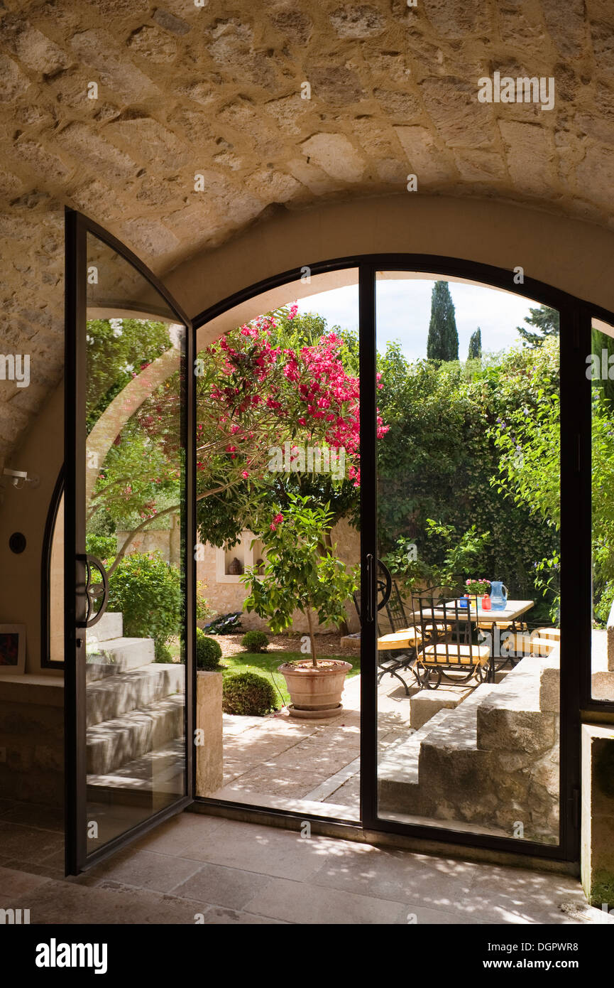 Un cavernoso spazio studio guardando fuori attraverso un arcuato finestra francese ad un cortile giardino Foto Stock