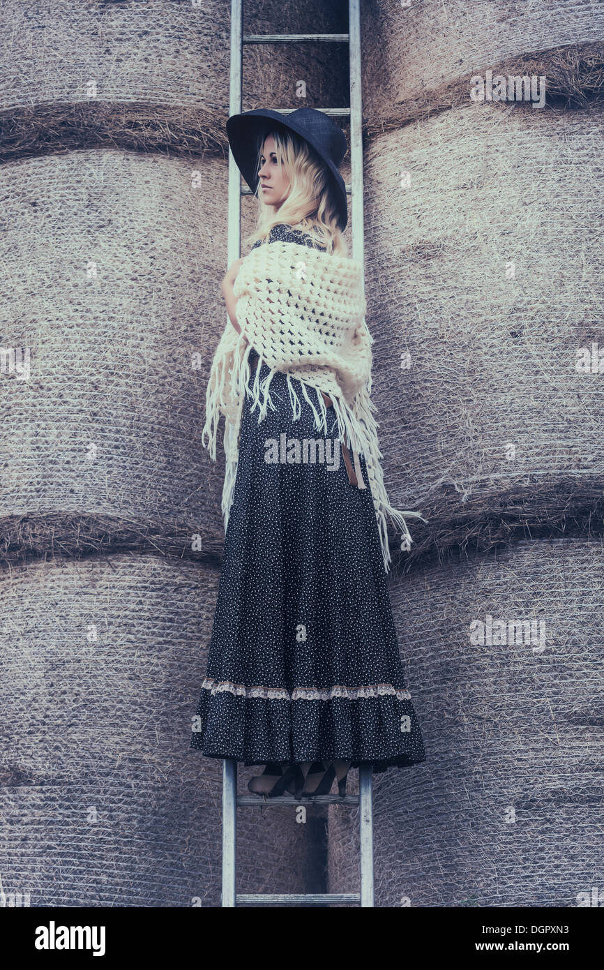 Una bella ragazza su una scala in un pagliaio Foto Stock