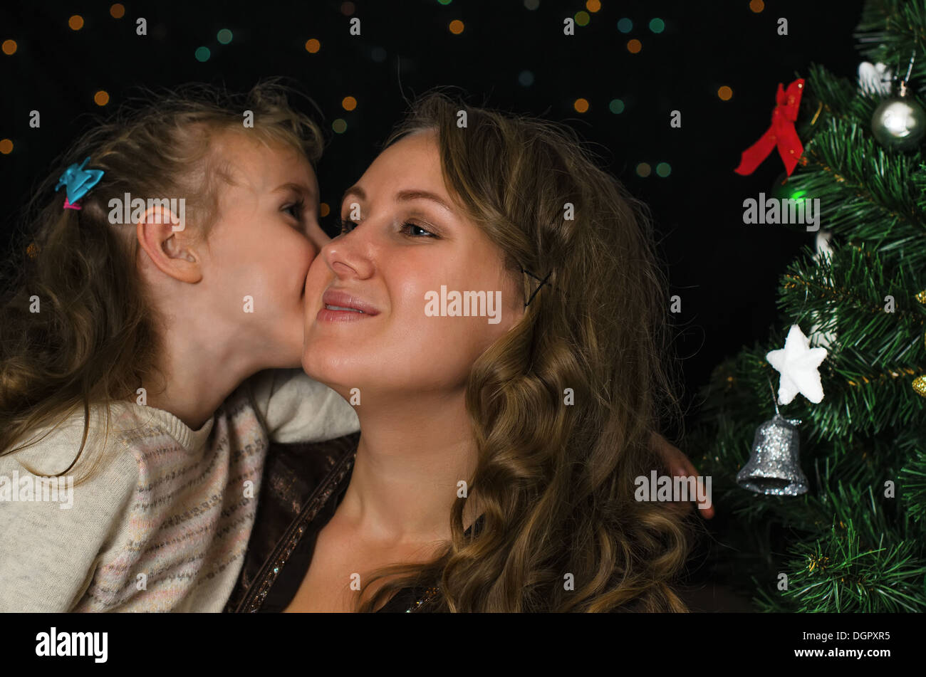 Piccola ragazza baciare sua madre nel tempo di Natale Foto Stock