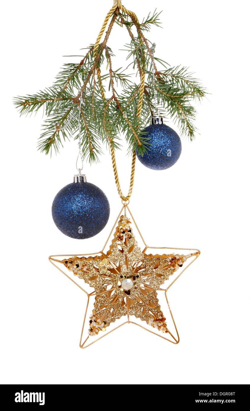 Stella d'oro e blu baubles appeso ad un ramo di un albero di Natale isolata contro bianco Foto Stock