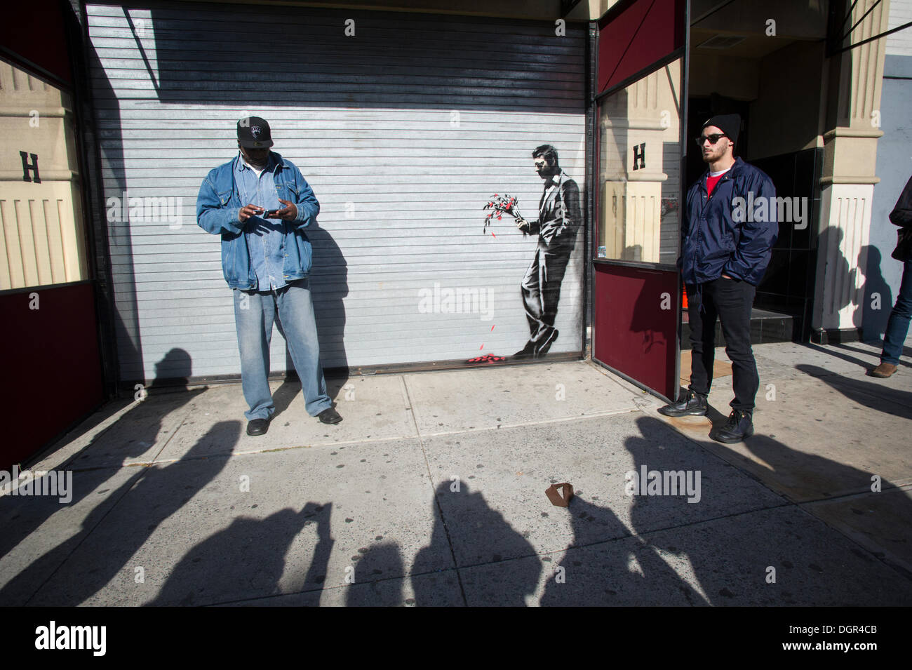 Street appassionati d arte gregge di Larry Flynt's Hustler Club di Hells Kitchen quartiere di New York il Giovedi, Ottobre 24, 2013 per vedere "aspettando invano" la ventiquattresima rata di Banksy graffiti dell'arte. La stampata artwork è sul roll-up porta d'ingresso al gentlemen's club, che ha inviato le guardie di sicurezza al di fuori di proteggere il loro nuovo capolavoro. Il fantomatico artista di strada è la creazione di opere intorno alla città ogni giorno durante il mese di ottobre è chiamato "Meglio fuori rispetto all'. (© Francesca M. Roberts) Foto Stock
