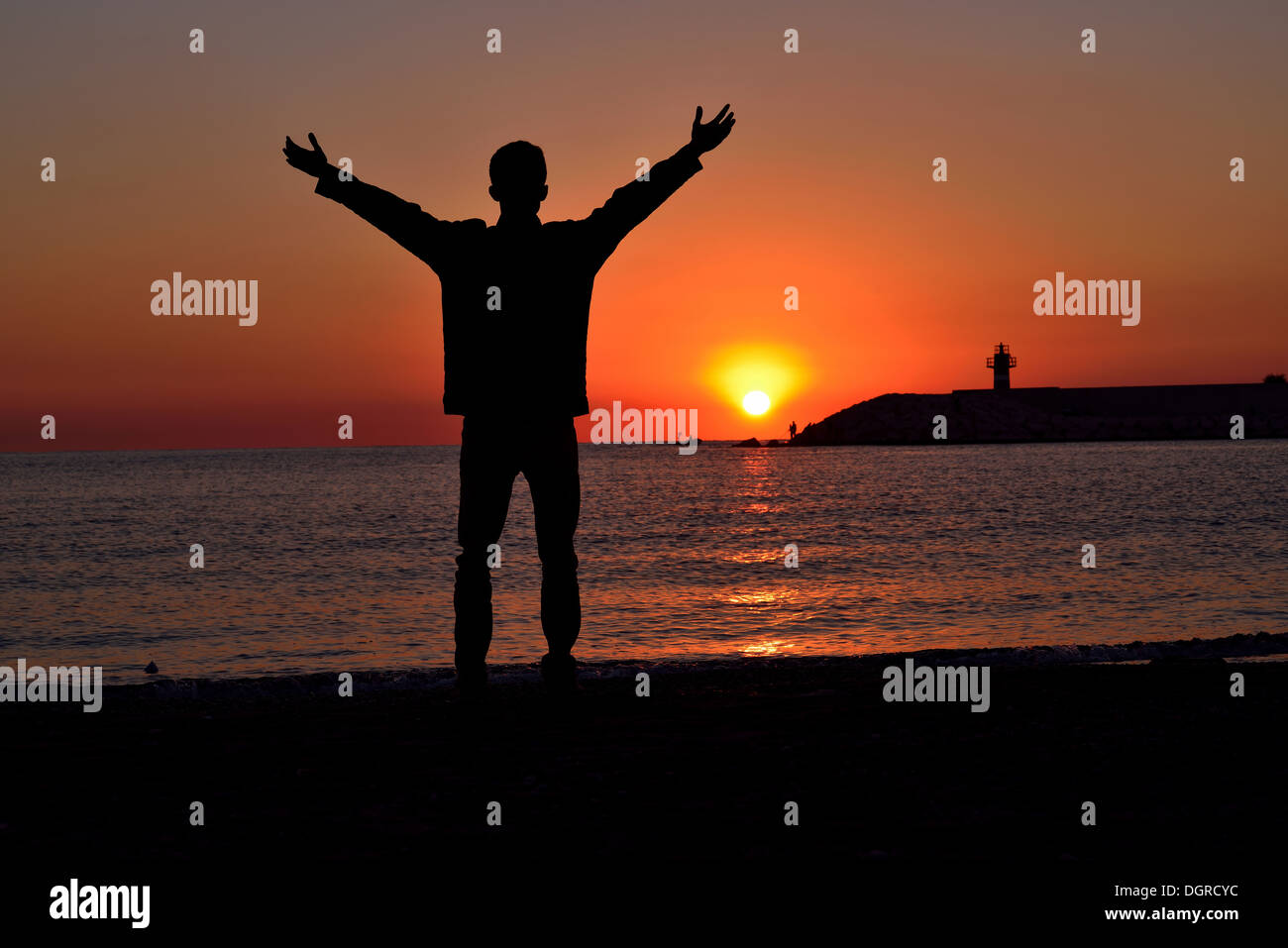 Silhouette di giovani permanente sulla spiaggia al tramonto Foto Stock