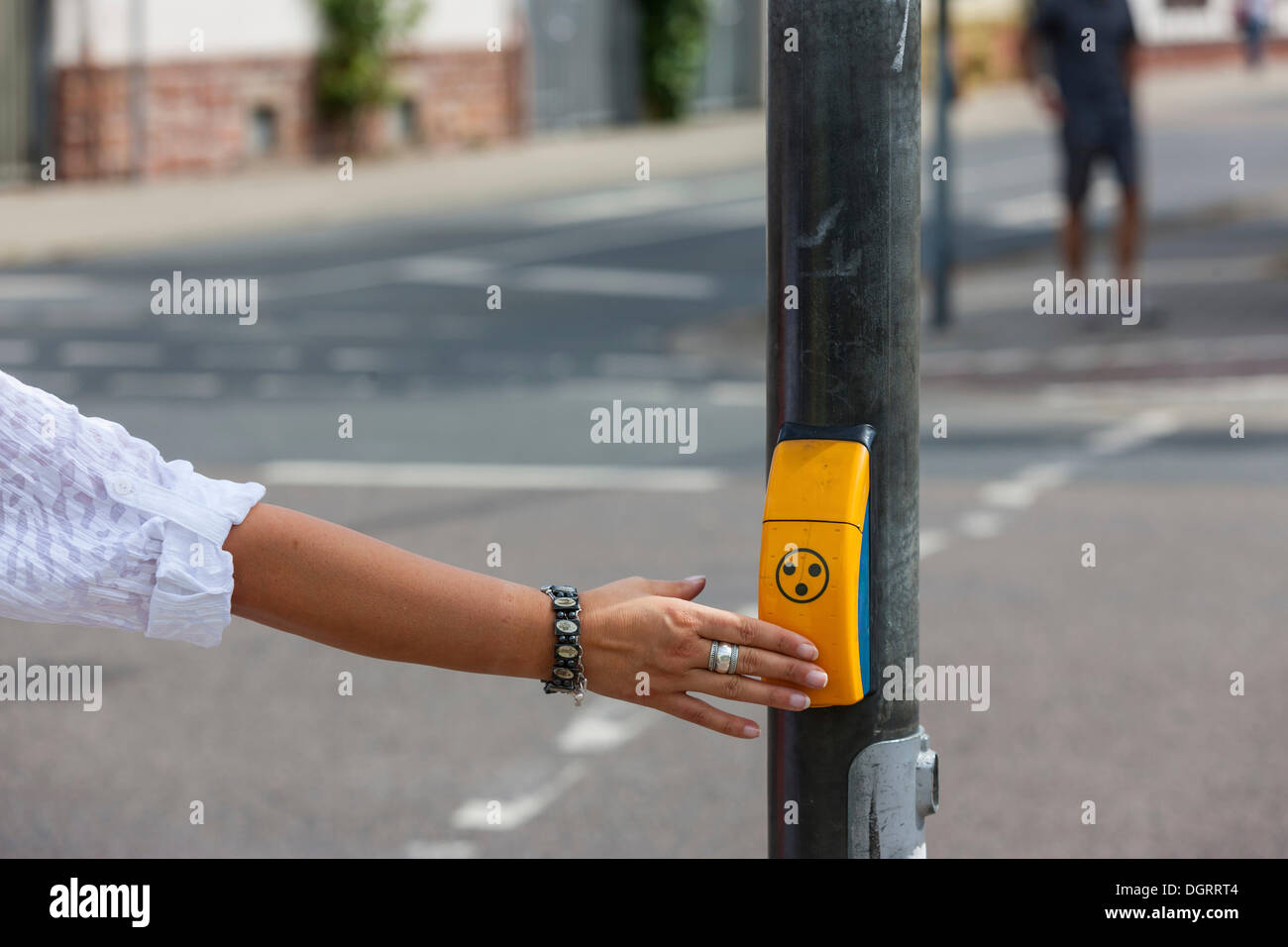 Donna premendo un pulsante per i non vedenti a un attraversamento pedonale, Hesse Foto Stock