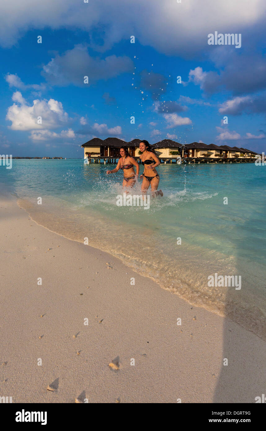 Due ragazze felici, circa 15 e 19 anni, in esecuzione su una spiaggia, laguna, Paradise Island all'indietro, Lankanfinolhu Foto Stock