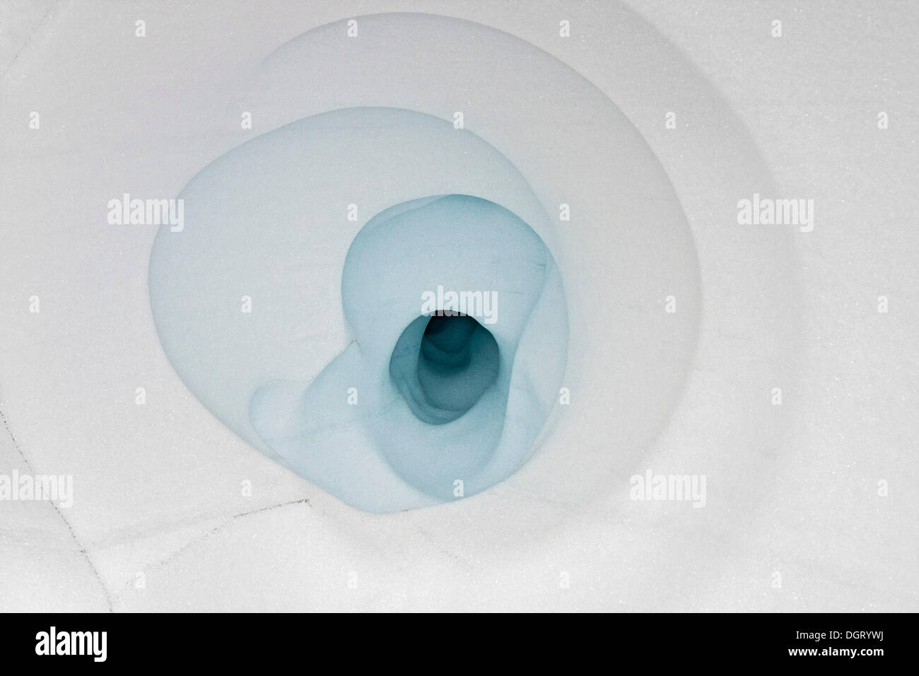 Buco Blu da acqua di fusione formante una spirale a forma di struttura geometrica nella neve del ghiacciaio di Kaldaklofsfjoell Foto Stock