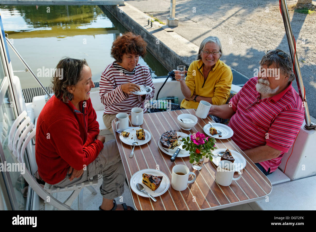 I turisti a bere caffè sulla terrazza posteriore di un Penichette, una casa galleggiante sul Canal des Vosges, precedentemente Canal de l'Est Foto Stock