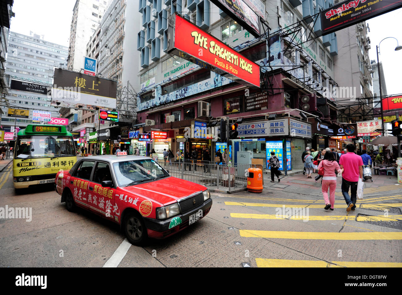 Un rosso taxi in attesa alle strisce pedonali su una strada del quartiere Tsim Sha Tsui, Kowloon, Hong Kong, Cina, Asia Foto Stock