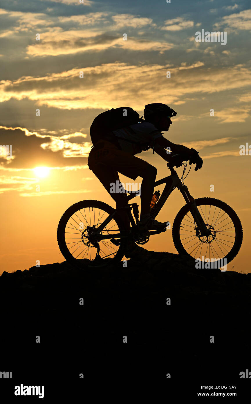Mountain Biker sul monte Kampenwand, silhouette contro la luce, Chiemgau, Alta Baviera, Baviera Foto Stock