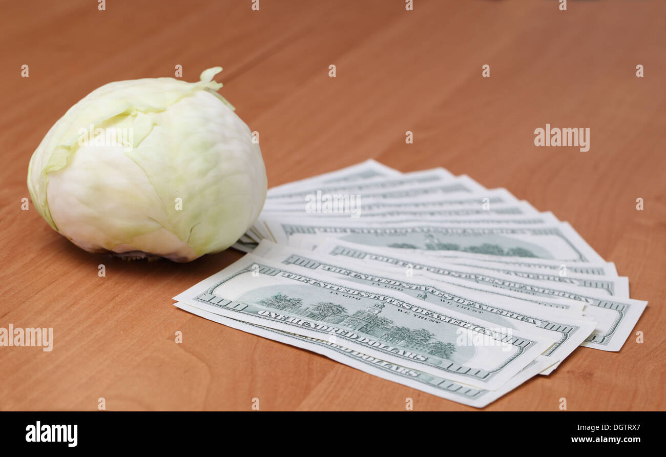 Cavolo e le fatture del dollaro sul tavolo di legno Foto Stock