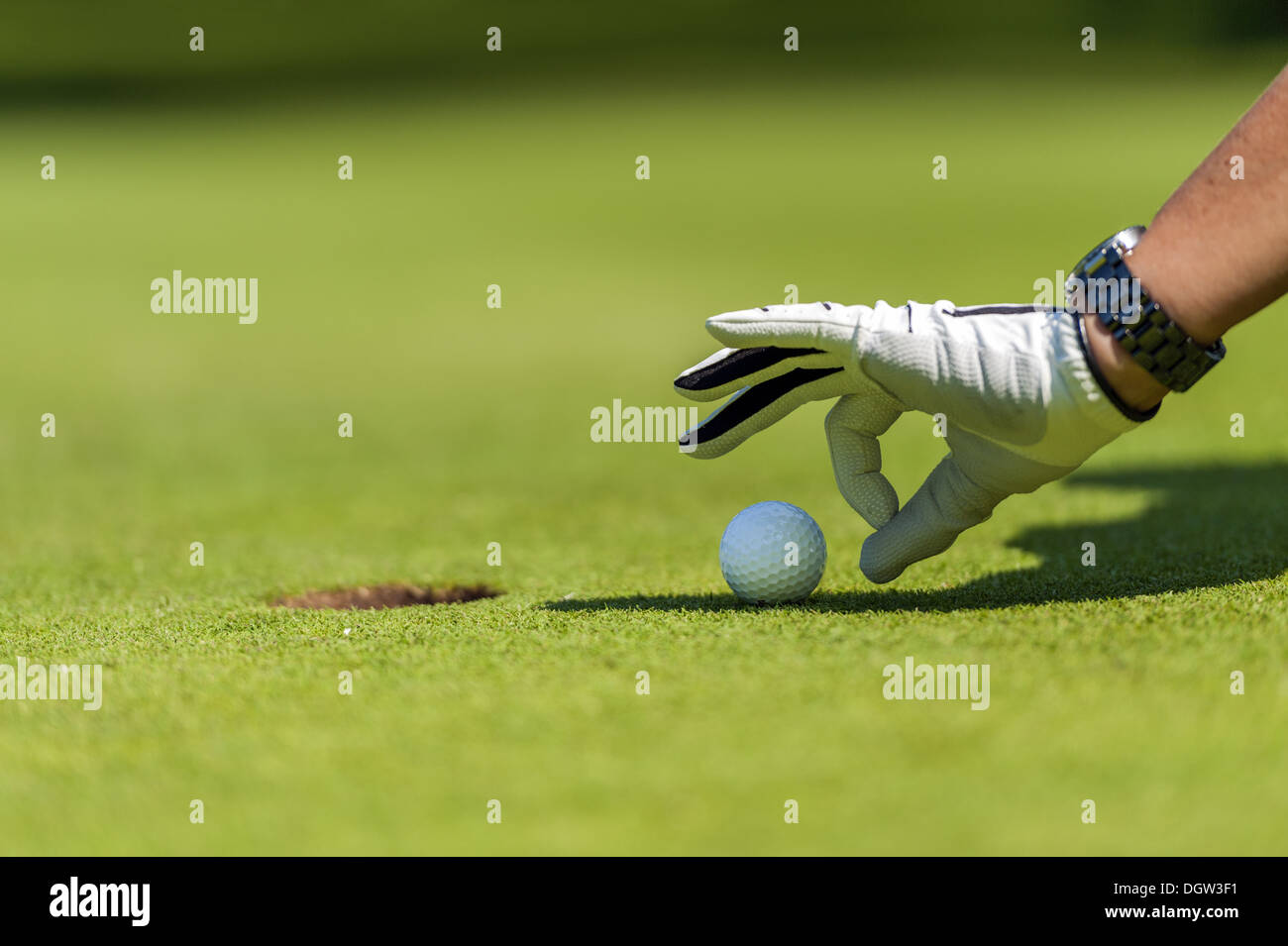 Dito sfiora la pallina da golf nel foro Foto Stock