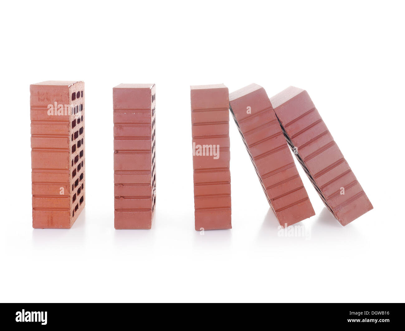 Linea di mattoni rossi con il primo mattone nella caduta successiva rendendo un effetto domino shot su bianco Foto Stock