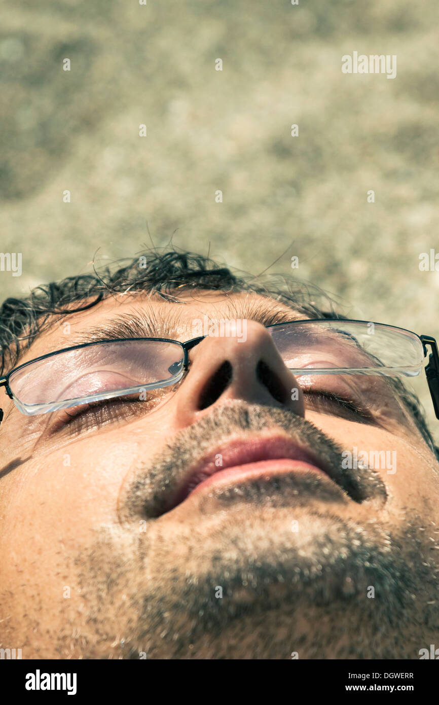 Primo piano di uomo di mezza età dormire sulla spiaggia. Foto Stock