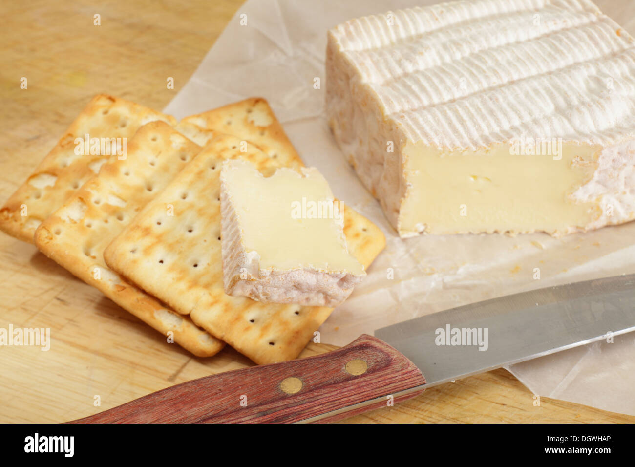 Il francese di Pont-l'Eveque Formaggio con biscotti e un coltello su un tagliere, Foto Stock