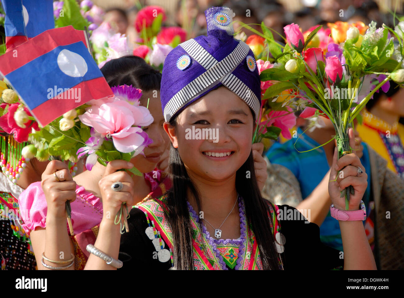 Parade, ritratto, sorridente ragazza di Hmong gruppo etnico, tradizionale copricapo, il laotiano bandiere, Xam Neua, bouquet Foto Stock