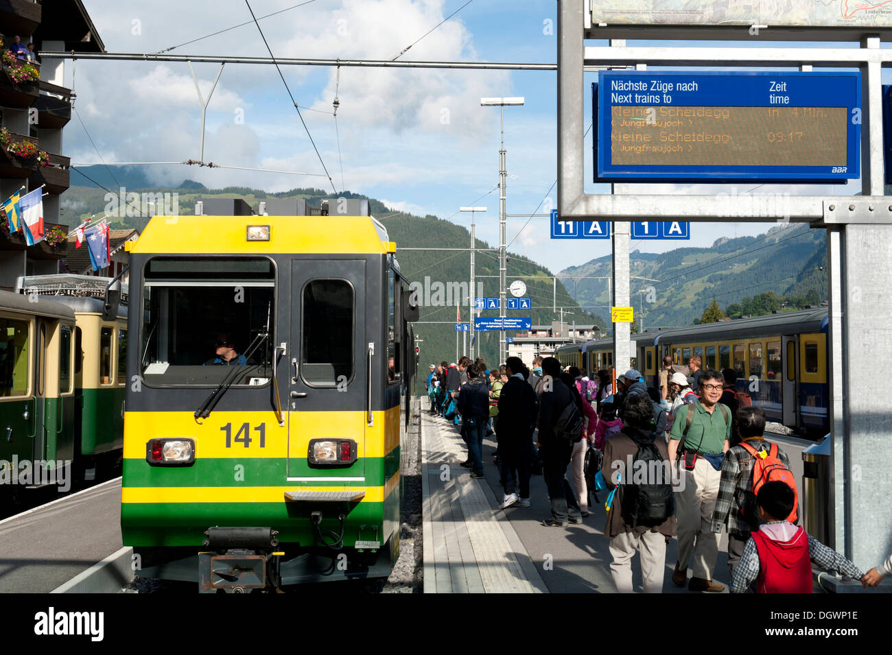 Treno e viaggiatori sulla piattaforma della stazione ferroviaria di Grindelwald, Oberland bernese, il Cantone di Berna, Alpi della Svizzera Foto Stock