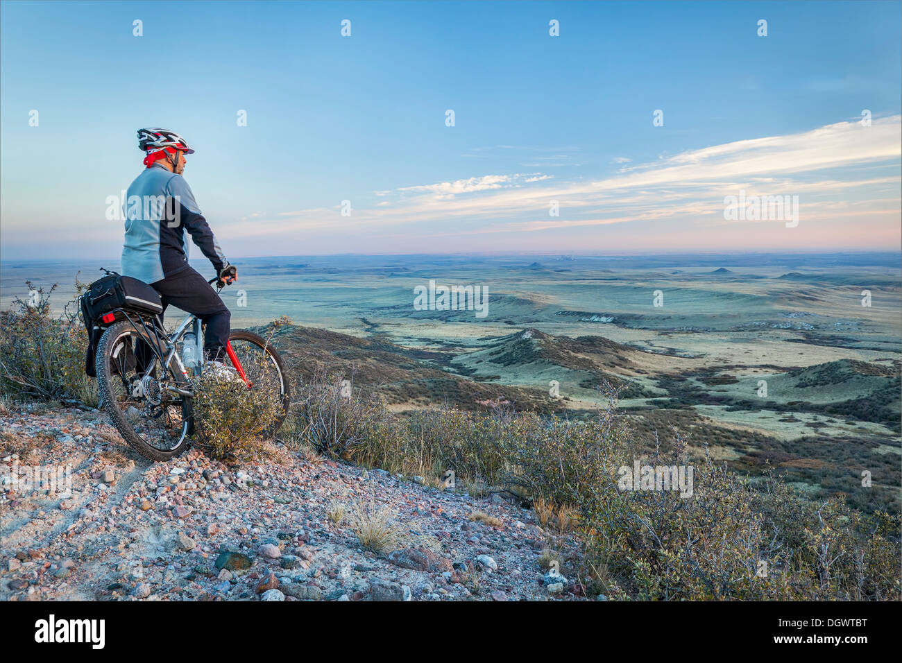 Senior maschio su una mountain bike contemplando una vista della prateria di rotolamento al crepuscolo, la pietra ollare Prairie Area naturale vicino a Fort Collins Foto Stock