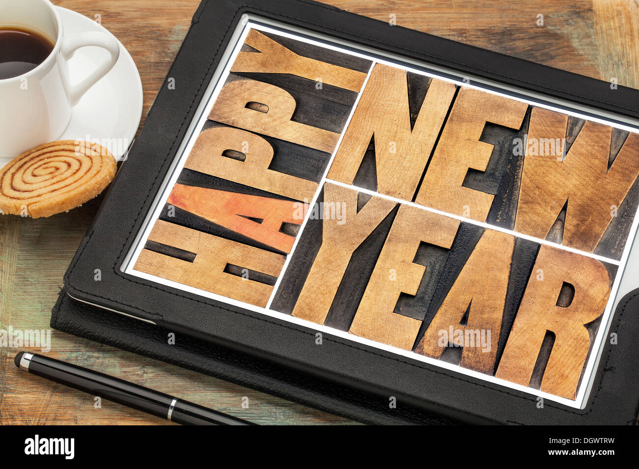 Felice anno nuovo in rilievografia tipo di legno sulla tavoletta digitale computer con penna stilo, tazza di caffè e cookie Foto Stock