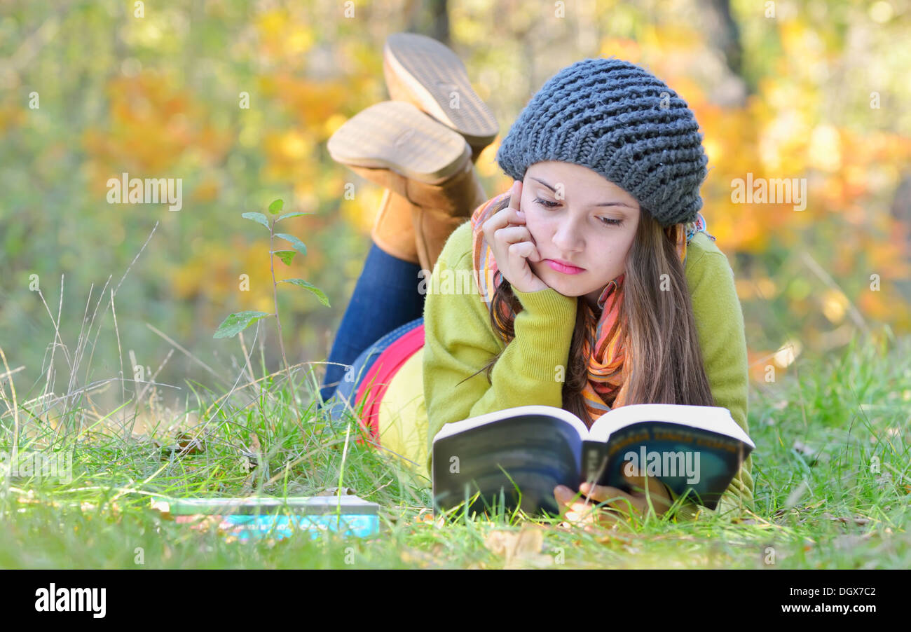 Bella ragazza leggendo un libro all'aperto nel periodo autunnale Foto Stock