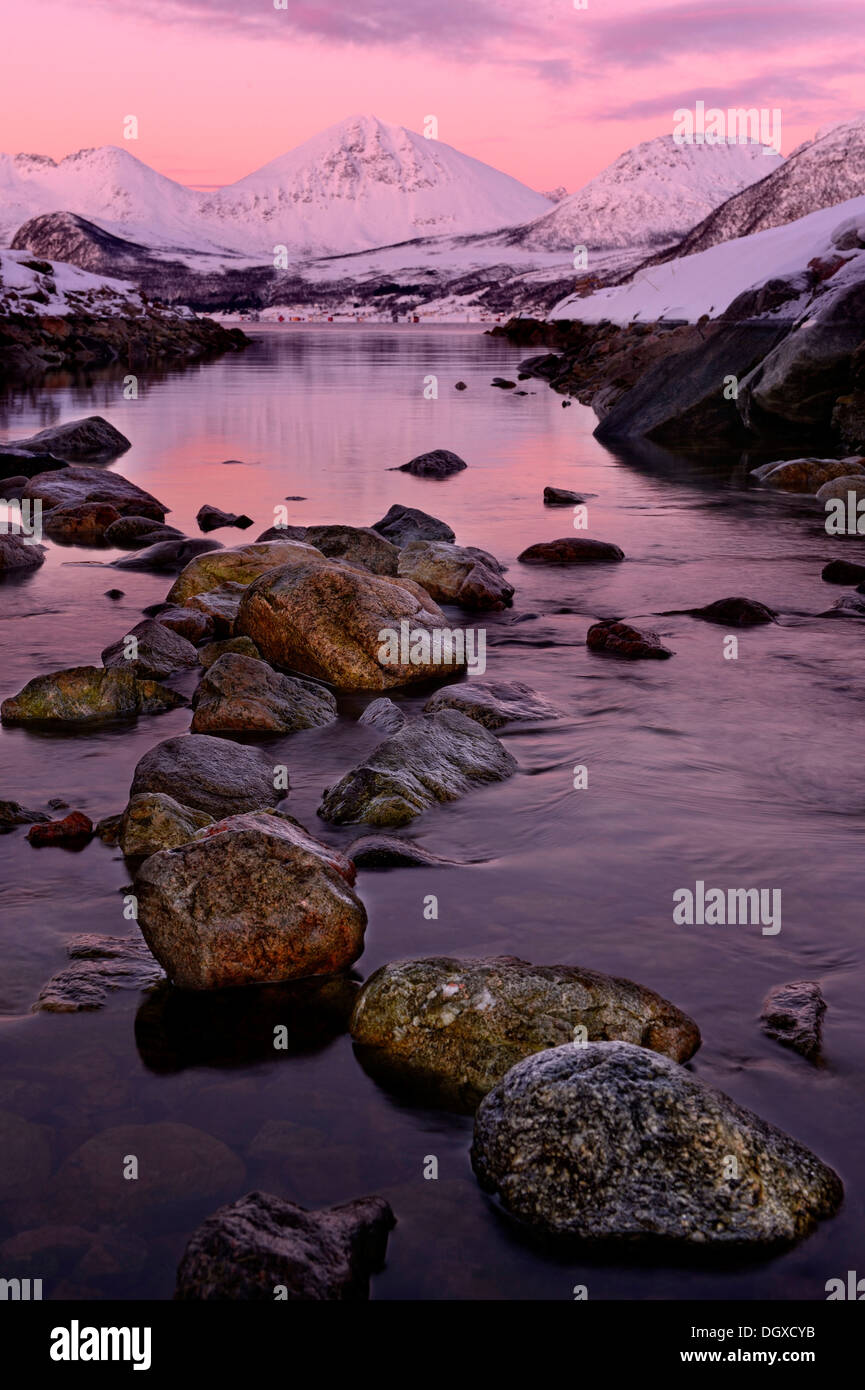 Fiordo con pietre di fronte ad una gamma di montagna nella luce della sera, Tromsø, ‪Troms, Norvegia settentrionale, Norvegia Foto Stock