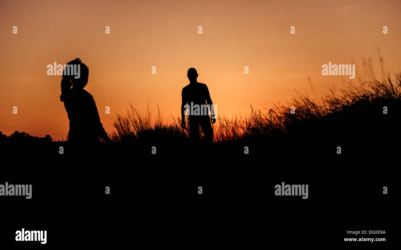 Donna che guarda la silhouette uomo venuto da fuori dell'orizzonte tramonto Foto Stock