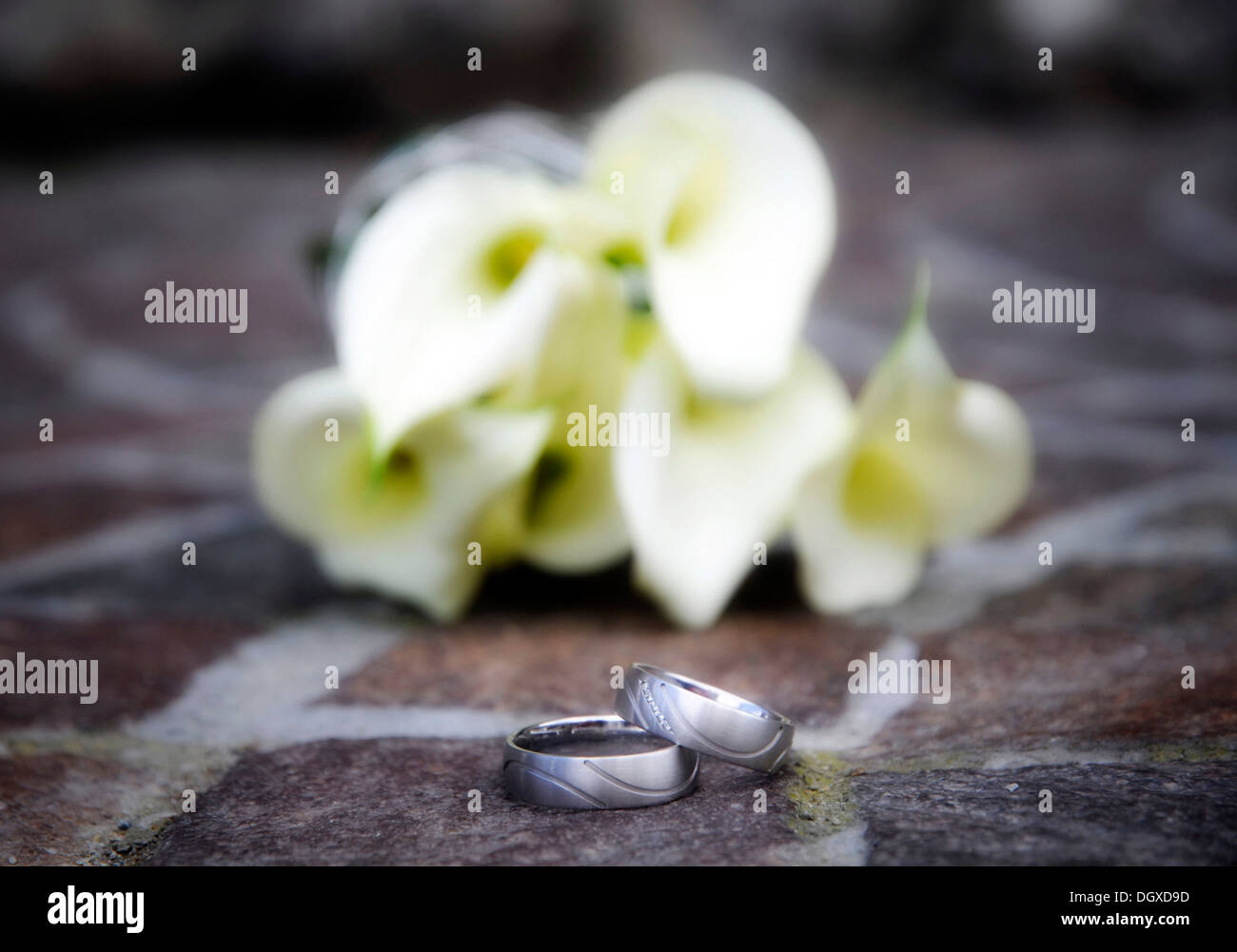 Gli anelli di nozze di fronte un bouquet nuziale Foto Stock