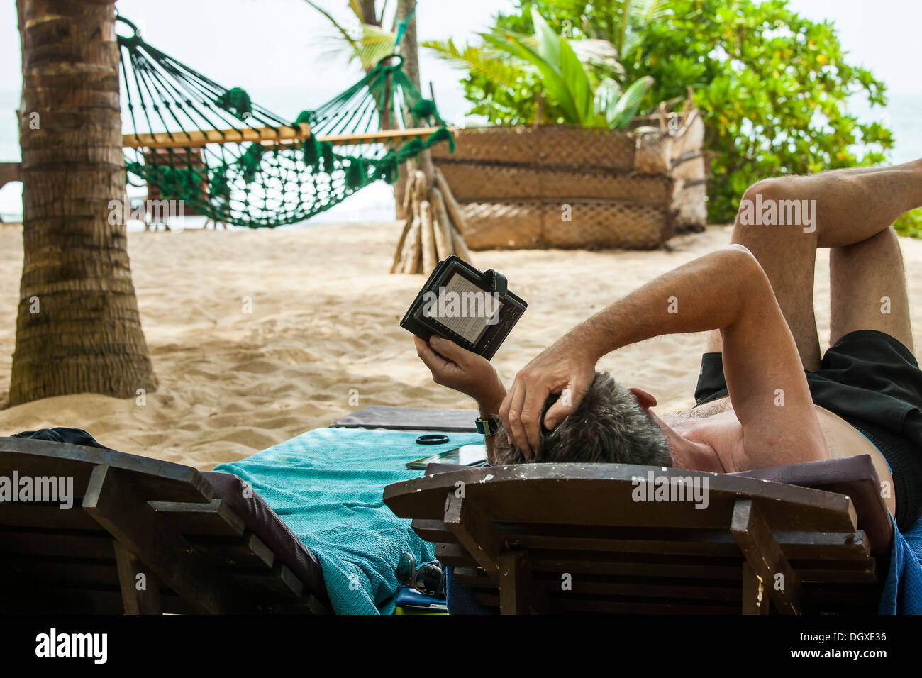 Un uomo la lettura di un libro e sulla spiaggia Foto Stock